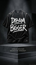 Black streetwear t-shirt with bold 'DREAM BIGGER' motivational typography design